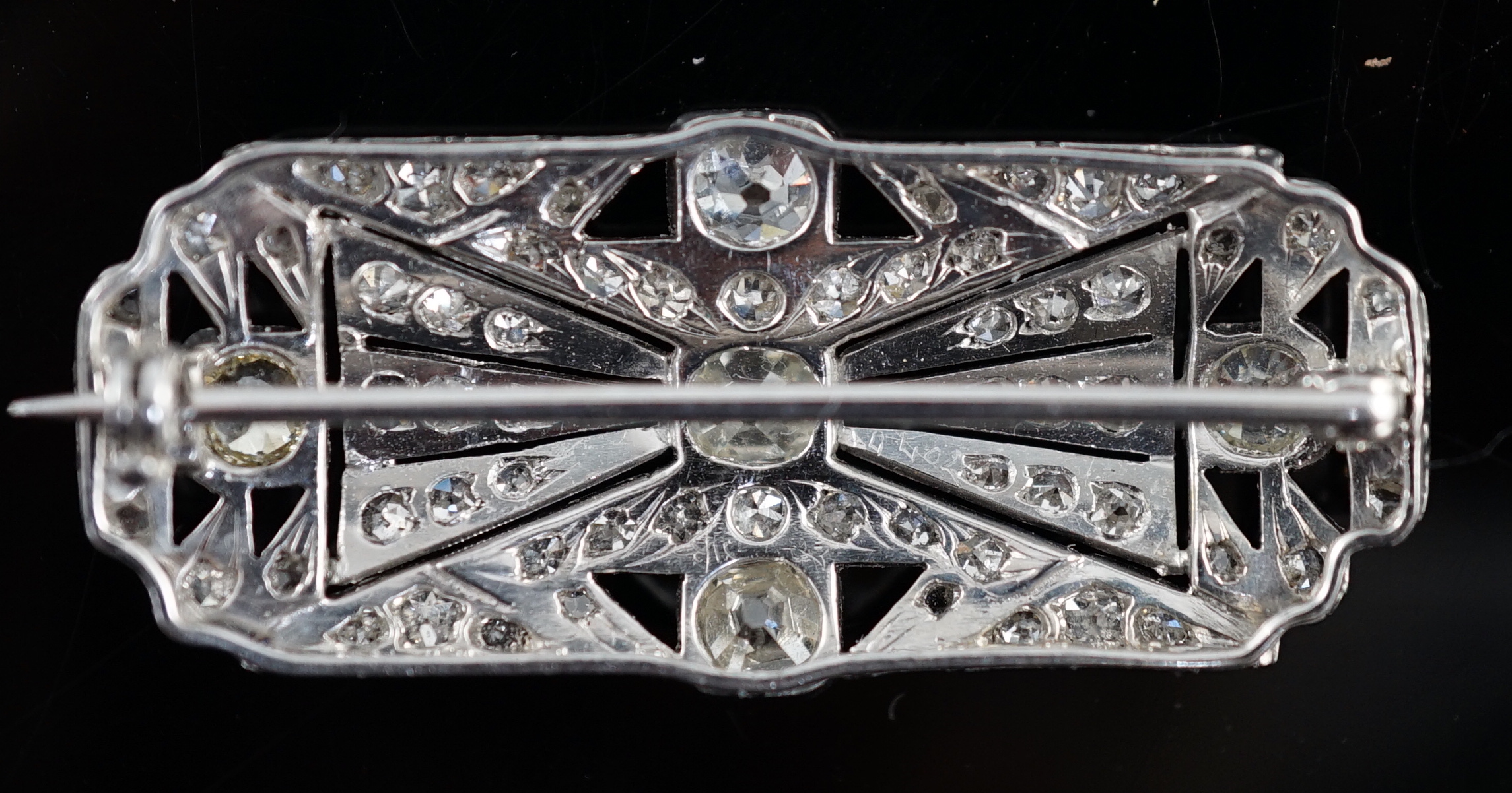 An Art Deco pierced platinum and millegrain set diamond cluster shaped rectangular brooch